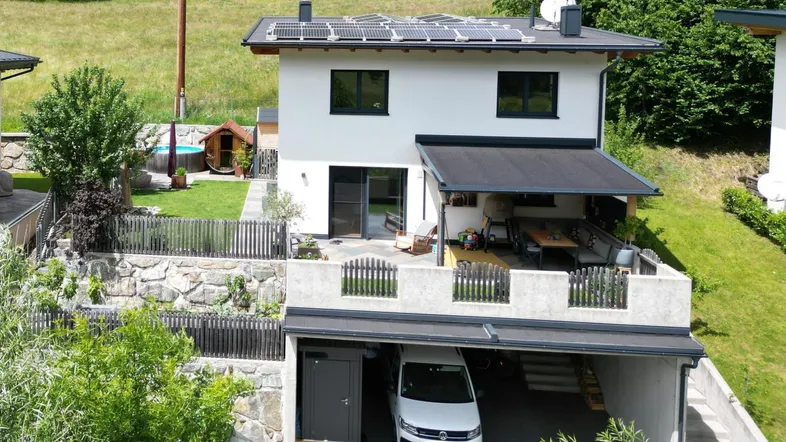 Modernes Einfamilienhaus mit Photovoltaikanlage, Carport, großer Terrasse und Garten mit kleinem Pool.