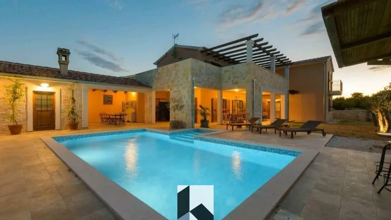 Luxuriöse Villa bei Sonnenuntergang mit großem Pool und Liegebereich im Freien.