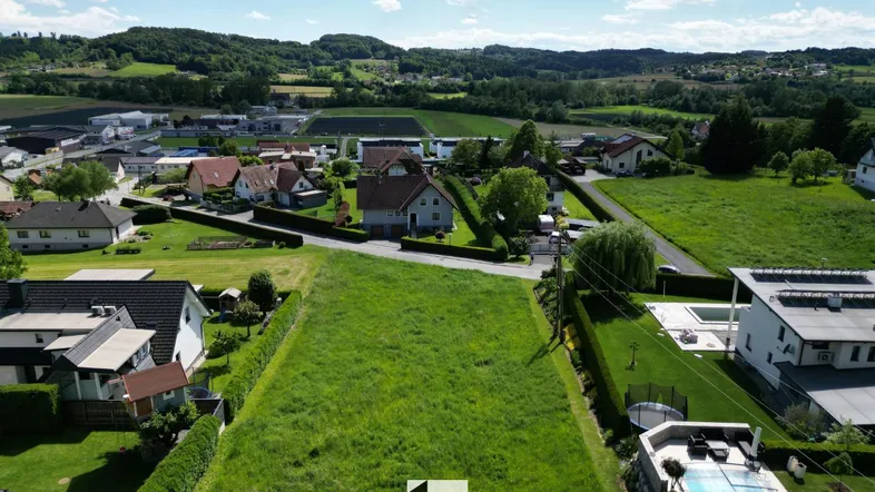 Luftaufnahme eines großen, grünen Grundstücks mit umliegenden Wohnhäusern und Hügellandschaft.