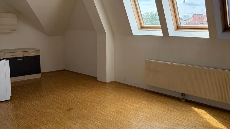Heller Wohnraum im Dachgeschoss mit schrägen Wänden, Dachfenstern und Laminatboden.