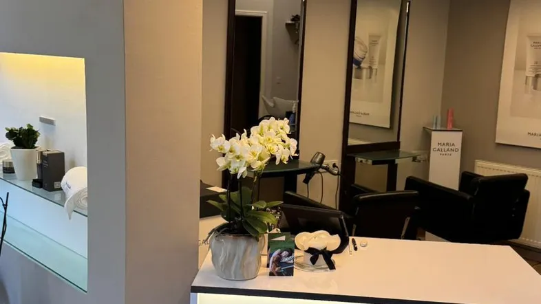 Empfangsbereich eines Salons mit modernem Design, stilvoller Beleuchtung und Markenlogo auf dem Tresen.