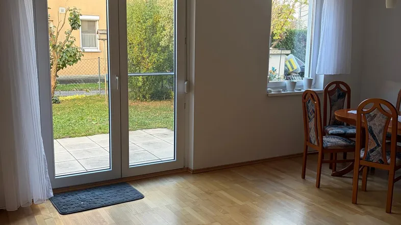 Helles Wohnzimmer mit Parkettboden und direktem Zugang zum gepflegten Gartenbereich.