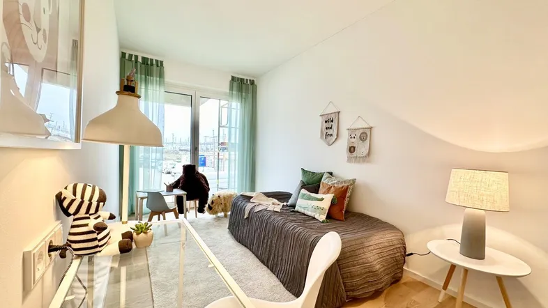 Helles Kinderzimmer mit Holzboden, Schrägdach und Zugang zu einem kleinen Balkon.