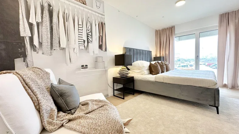 Helles Schlafzimmer mit großem Bett, integriertem Kleiderschrank und Zugang zum Balkon.