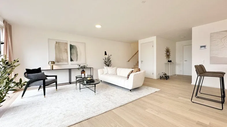 Helles, modernes Wohnzimmer mit Parkettboden, weißem Sofa und stilvollen Möbeln in einem Neubau.