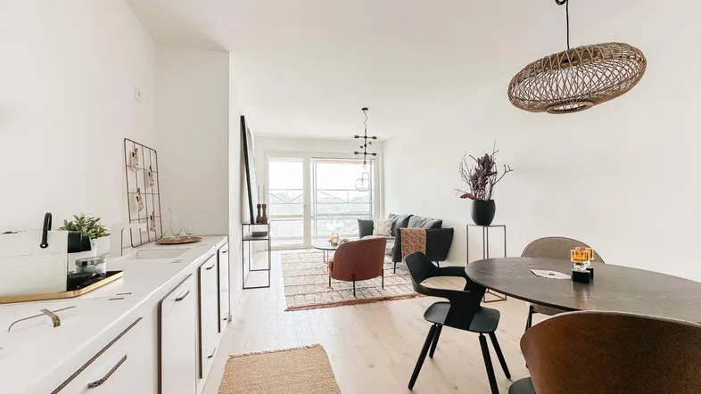 Heller, offener Wohn- und Essbereich mit integrierter Küchenzeile und Zugang zum Balkon.