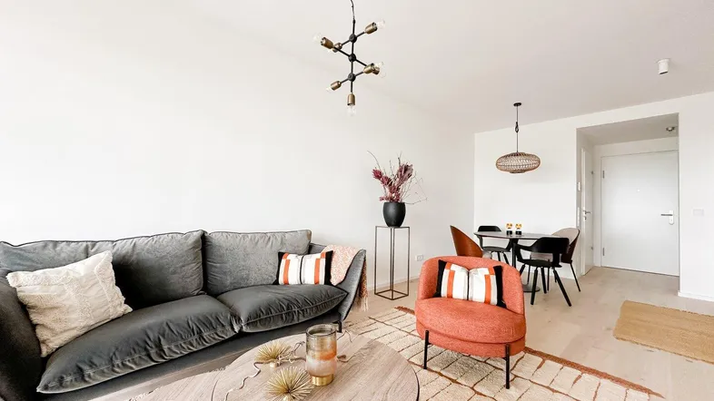 Helles Wohn- und Esszimmer mit modernem Sofa, Sessel und Esstisch, ideal für geselliges Beisammensein.