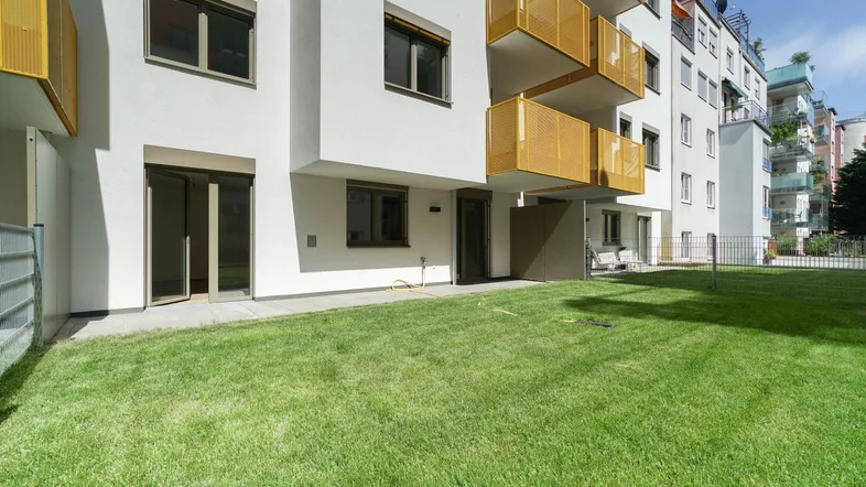 Neubau-Fassade mit modernem Design und direktem Zugang zu einer gepflegten Rasenfläche.