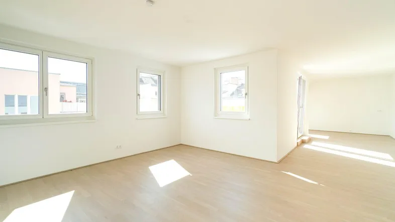 Helles, leeres Zimmer mit Parkettboden und mehreren Fenstern, bereit zur individuellen Gestaltung.
