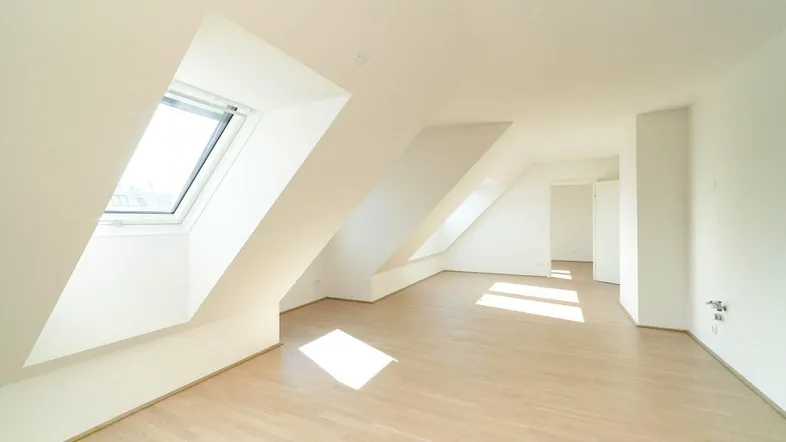 Helles Dachgeschosszimmer mit schrägen Wänden, Dachfenstern und hellem Parkettboden, ideal für Wohnzwecke.