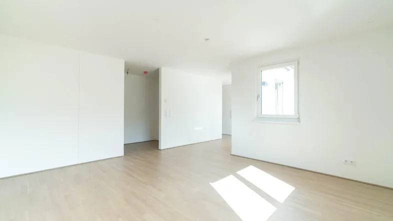 Helles Zimmer mit Parkettboden und viel Tageslicht, ideal als Wohn- oder Schlafbereich.