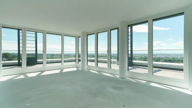 Heller, unmöblierter Raum mit großen Fenstern und weitem Ausblick über die Landschaft.