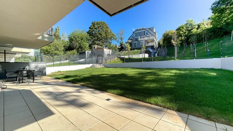 Geräumige Terrasse mit Sitzgelegenheiten und angrenzendem Rasenbereich, ideal für Entspannung im Freien.