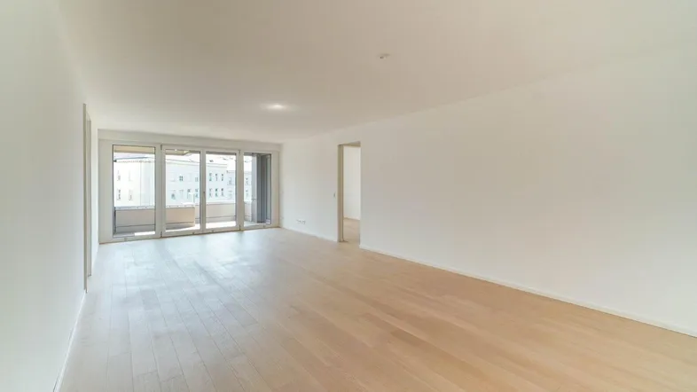 Helles, leeres Wohnzimmer mit Holzboden und Zugang zu einem Balkon, bereit zur individuellen Gestaltung.