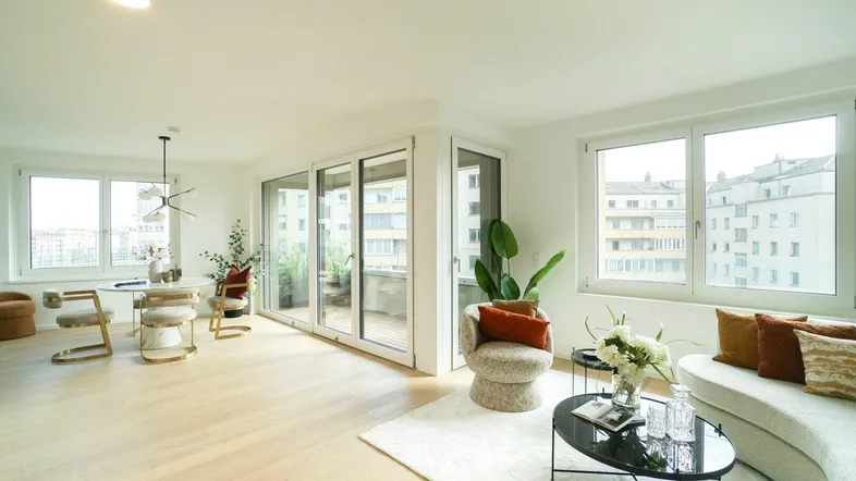 Helles, offenes Wohn-Esszimmer mit modernem Design, Parkettboden und Zugang zum Balkon.