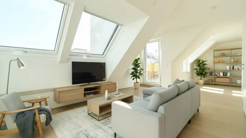 Helles Wohnzimmer im Dachgeschoss mit großen Dachfenstern und modernem Mobiliar.