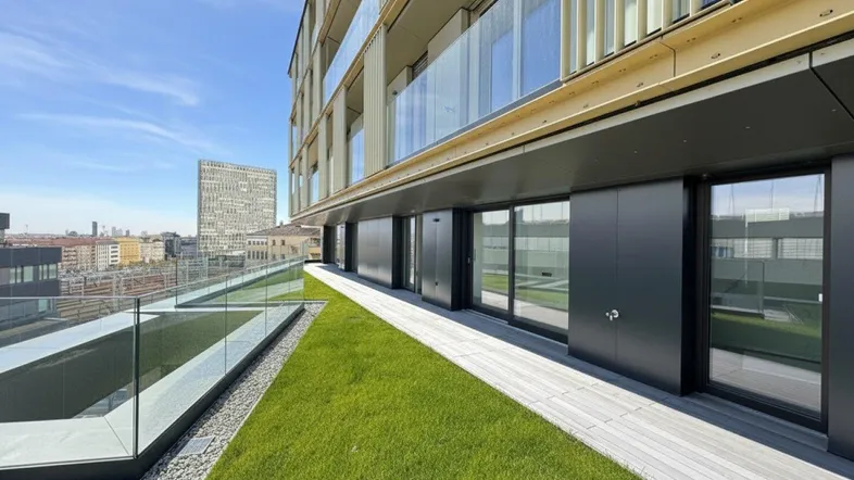 Große Dachterrasse mit Rasenfläche, Holzbelag und weitem Blick über die Stadt.