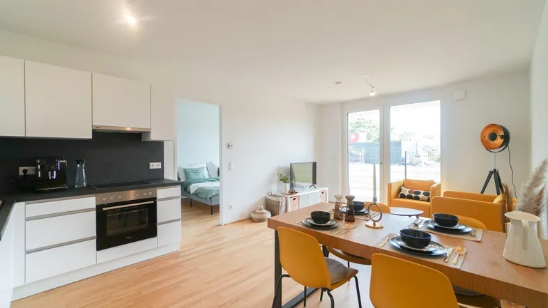Moderne offene Küche mit Essbereich und hellem Wohnzimmer, ausgestattet mit Holzboden und großen Fenstern.