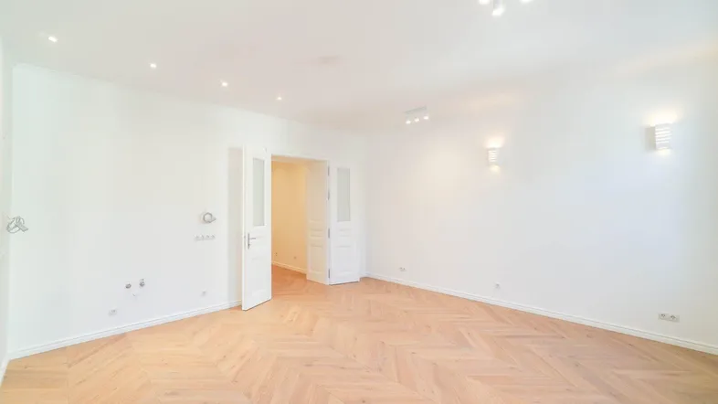 Helles Zimmer mit elegantem Fischgrätparkett und weißen Wänden, bereit zur individuellen Gestaltung.