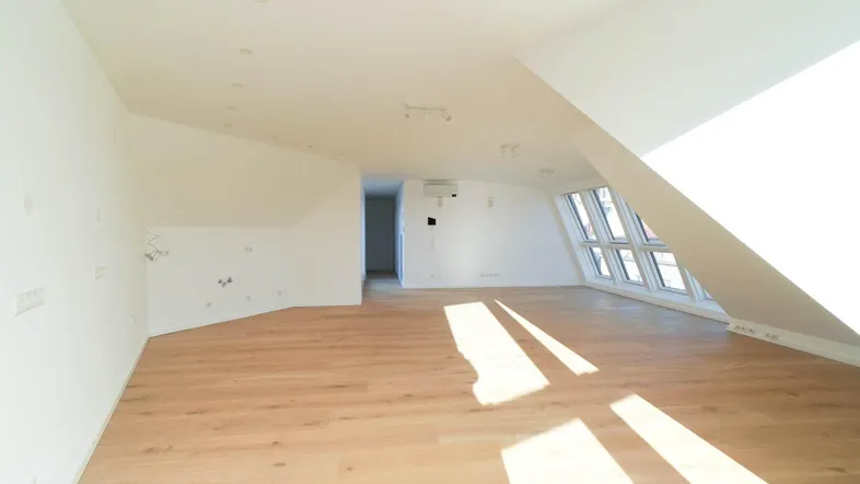 Helles, leeres Dachgeschosszimmer mit Holzboden und großen Fenstern, bereit zur individuellen Gestaltung.