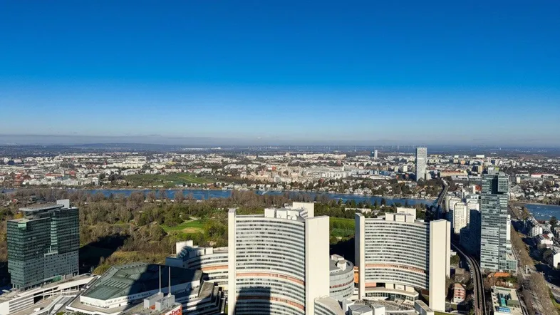 Panoramablick auf die Stadt mit Fluss und modernen Gebäuden unter blauem Himmel.