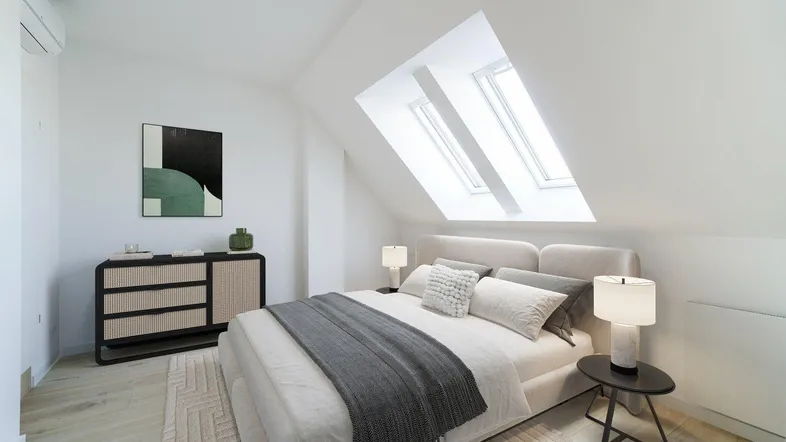 Helles Schlafzimmer im Dachgeschoss mit schrägen Wänden, Dachfenstern und modernem Interieur.