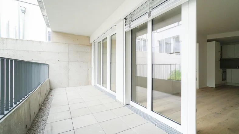 Heller, gefliester Balkon mit Betonwänden und Blick auf den Innenhof, ideal für entspannte Stunden im Freien.