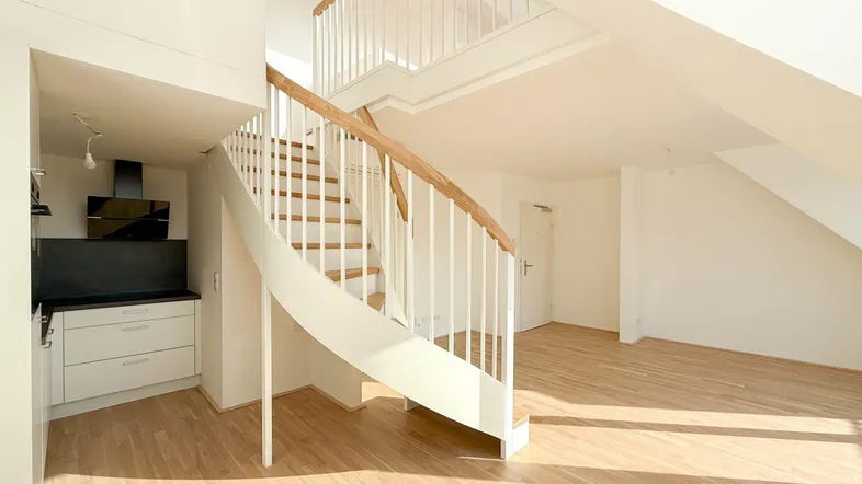 Heller offener Wohnbereich mit integrierter Küche und moderner Wendeltreppe zum oberen Geschoss.