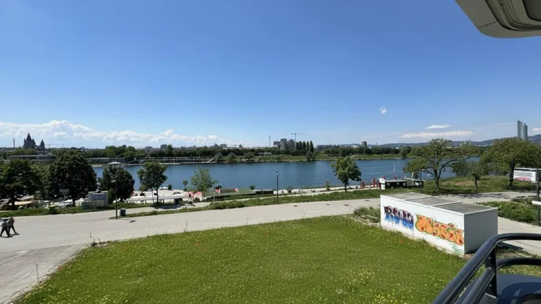 Panoramablick vom Balkon auf die Donau und die Stadtlandschaft unter blauem Himmel.