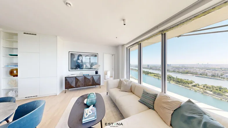Helles Wohnzimmer mit großen Fenstern, die einen weiten Blick auf den Fluss und die Stadt bieten.