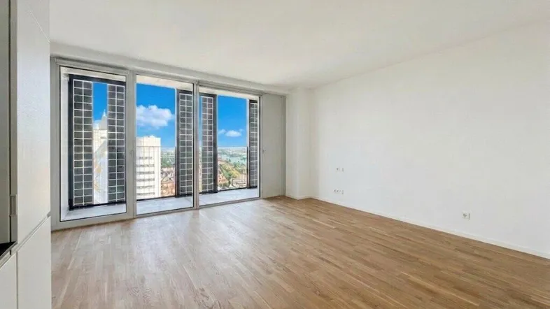 Heller Wohnraum mit großen Fenstern, Holzboden und weitem Blick über die Stadt.