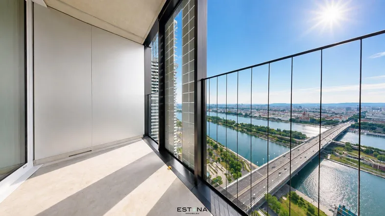 Heller Balkon mit Glasgeländer und weitem Blick über die Donau und die Stadt.