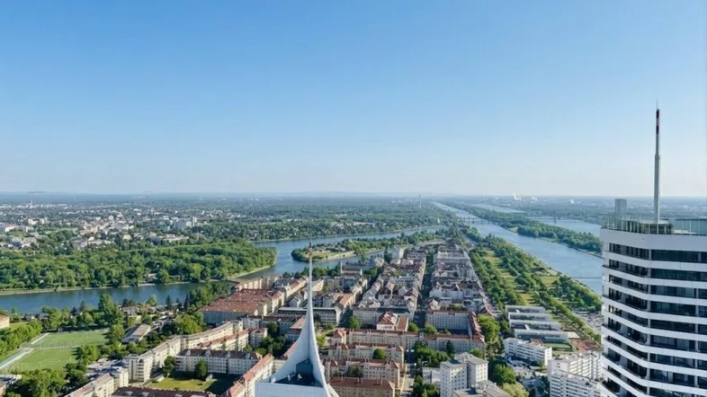 Weitläufiger Blick über die Stadt, die Donau und die umliegende grüne Landschaft von oben.