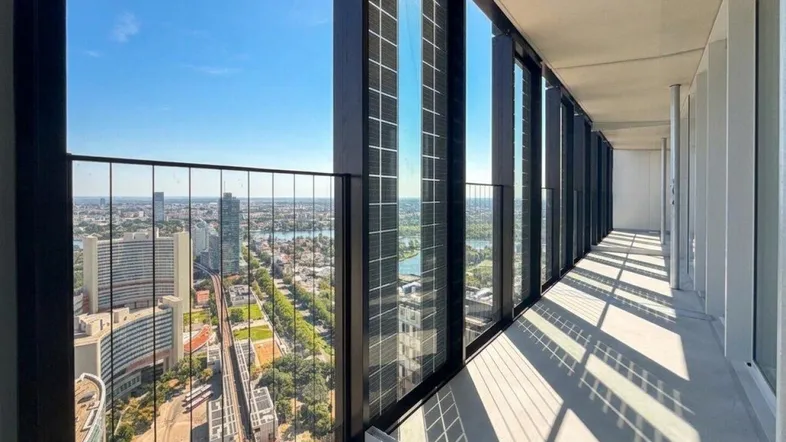 Langer Balkon mit Glasgeländer und weitem Blick über die Stadt und den See.