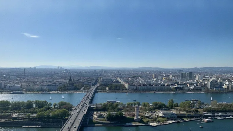 Weitläufiger Blick über die Stadt, den Fluss und eine Brücke unter blauem Himmel.