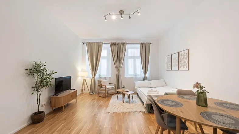 Helles Studio-Apartment mit Parkettboden, Essbereich und Schlafgelegenheit in modernem Stil.