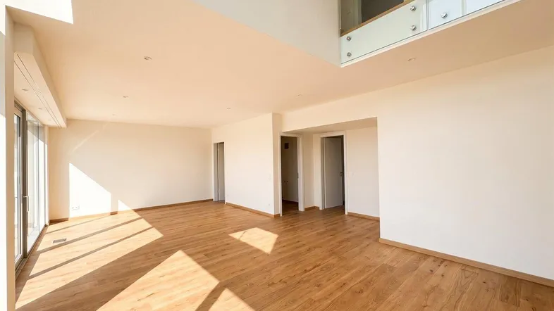 Helles, geräumiges Wohnzimmer mit Holzboden, hohen Decken und viel Tageslicht.