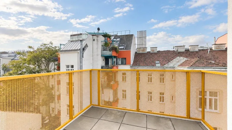 Geräumige Terrasse mit gelbem Geländer und Blick auf die umliegenden Gebäude der Stadt.