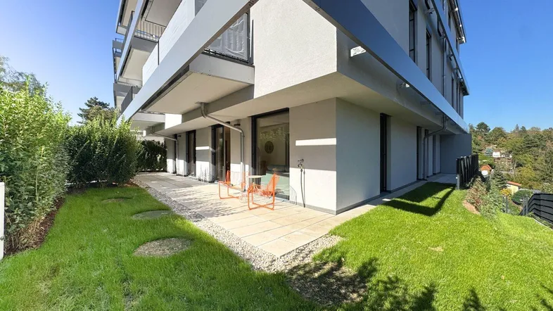 Moderne Wohnanlage mit gepflegtem Gartenbereich und einer kleinen Terrasse mit Sitzgelegenheiten.
