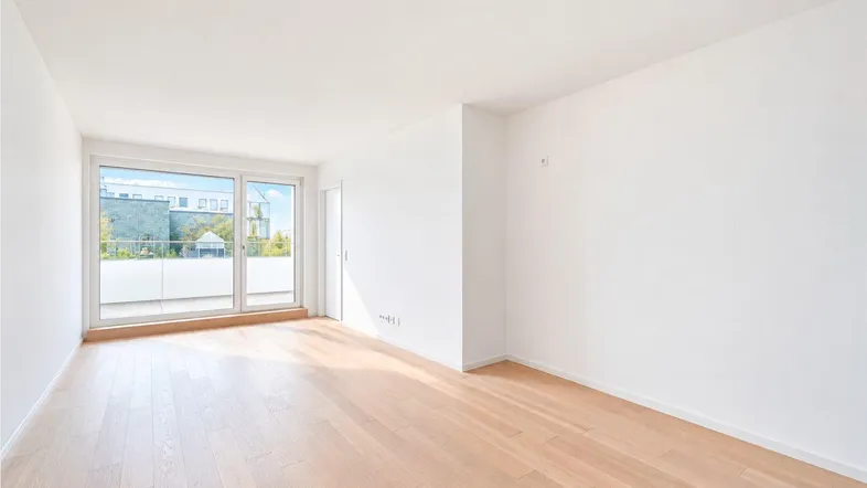 Helles Zimmer mit Parkettboden und Zugang zu einem Balkon, ideal für Wohn- oder Schlafbereich.