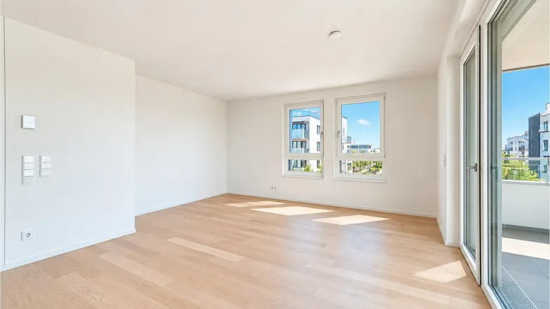 Helles, unmöbliertes Zimmer mit Parkettboden, großen Fenstern und Zugang zum Balkon.