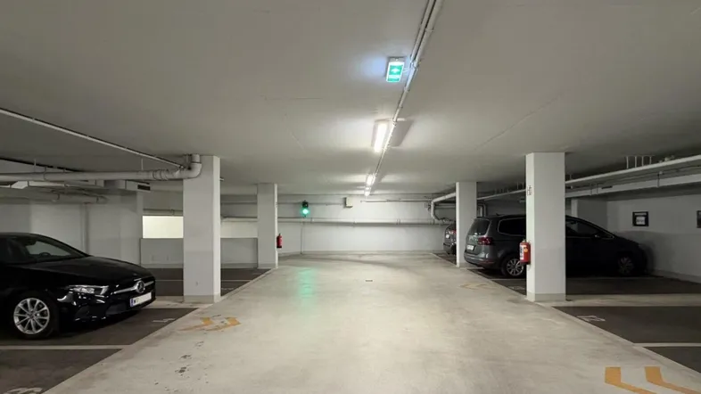 Helle Tiefgarage mit mehreren Stellplätzen und geparkten Fahrzeugen, gut beleuchtet.