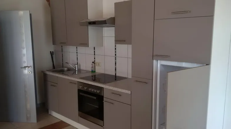 Funktionale Küche mit grauen Schränken, integrierten Geräten und Fliesenrückwand.