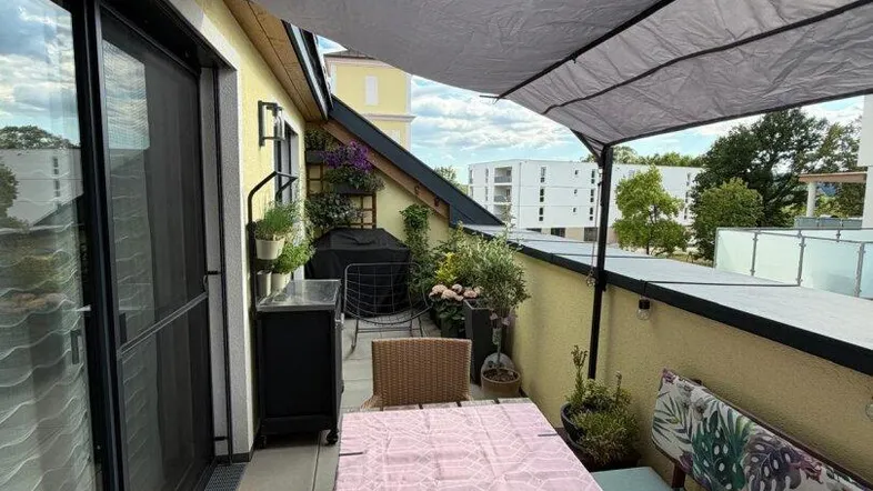 Überdachter Balkon mit Esstisch, Sitzbank und Pflanzen, ideal für entspannte Stunden im Freien.