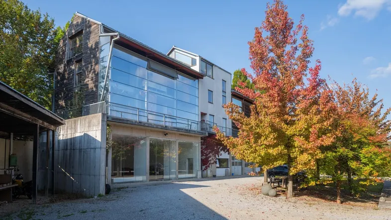 Modernes Gebäude mit Glasfassade und Holzverkleidung, umgeben von Herbstbäumen.