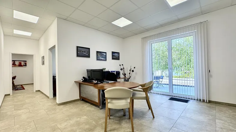Helles Büro mit modernen Fliesen, großen Fenstern und Zugang zu einem Außenbereich.