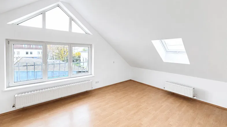 Helles Dachgeschosszimmer mit Laminatboden, großen Fenstern und einem Dachfenster.