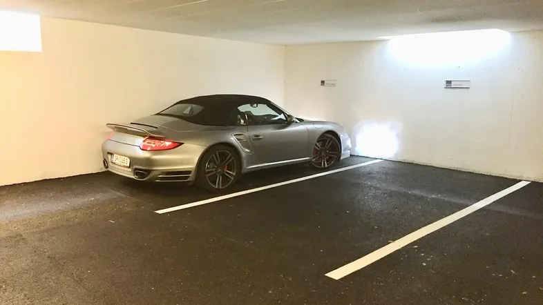 Silberner Sportwagen parkt auf einem Stellplatz in einer hell beleuchteten Tiefgarage.