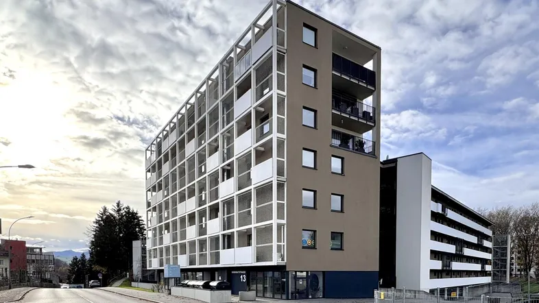 Modernes Mehrfamilienhaus mit vielen Balkonen und einer ansprechenden Fassadengestaltung unter bewölktem Himmel.