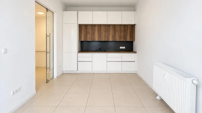 Heller Raum mit moderner Einbauküche, Fliesenboden und Heizkörper, ideal für ein Büro oder eine kleine Wohneinheit.
